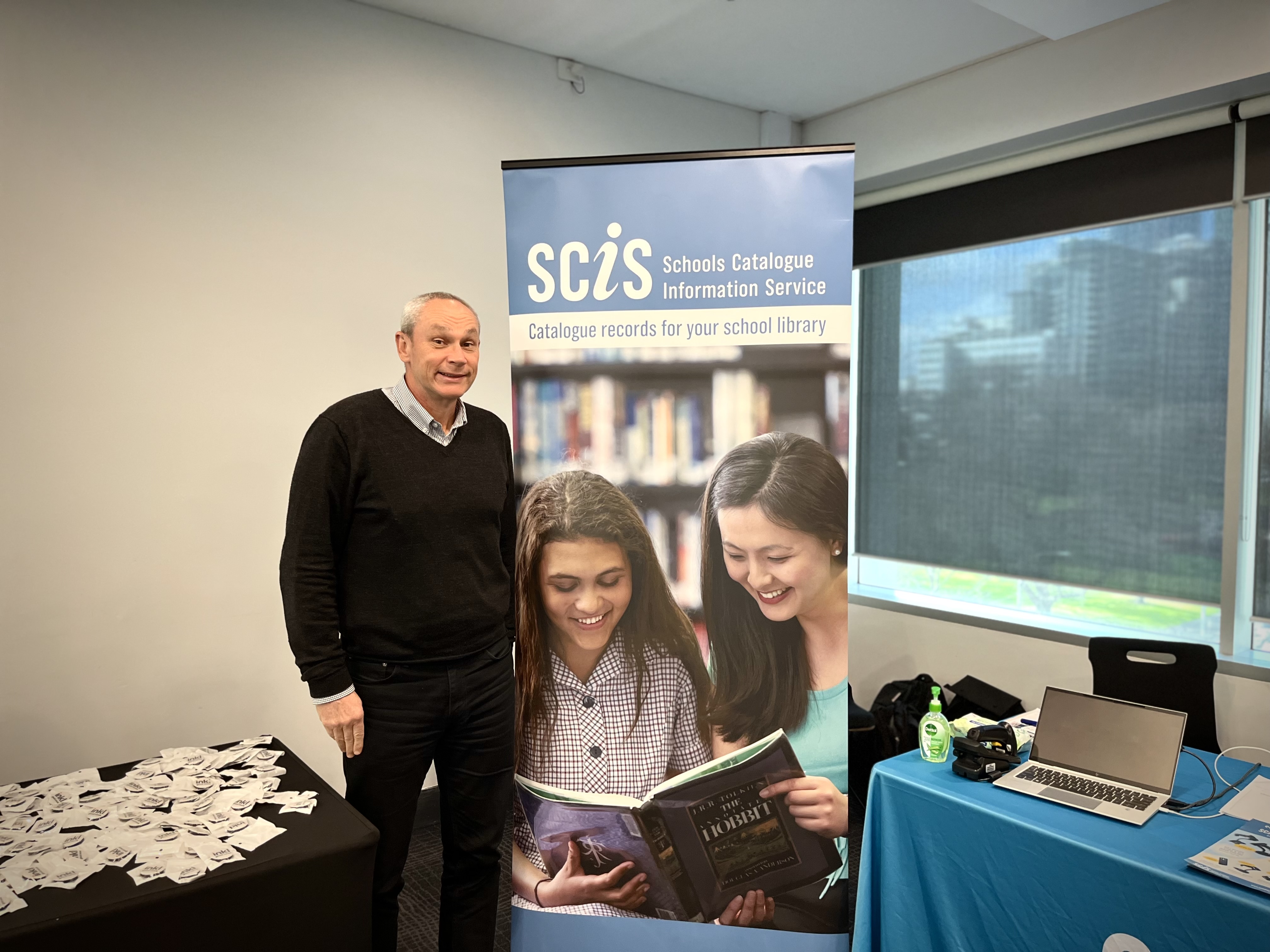 Anthony Shaw standing next to a SCIS banner the School Library Association of Victoria's September Symposium
